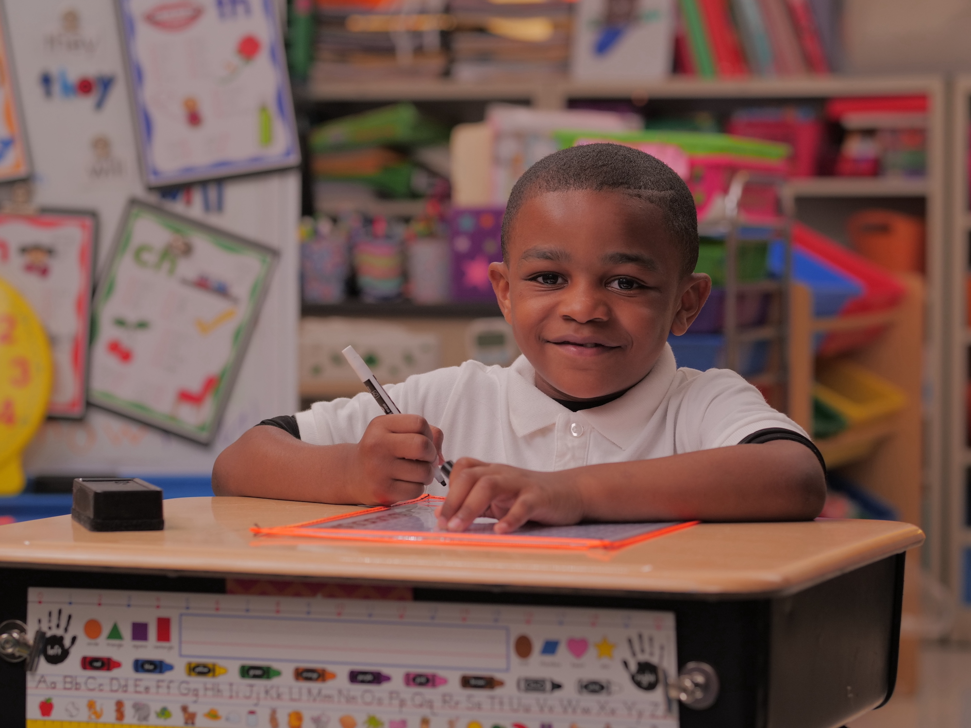 YCS Student Smiling Sitting at a Desk