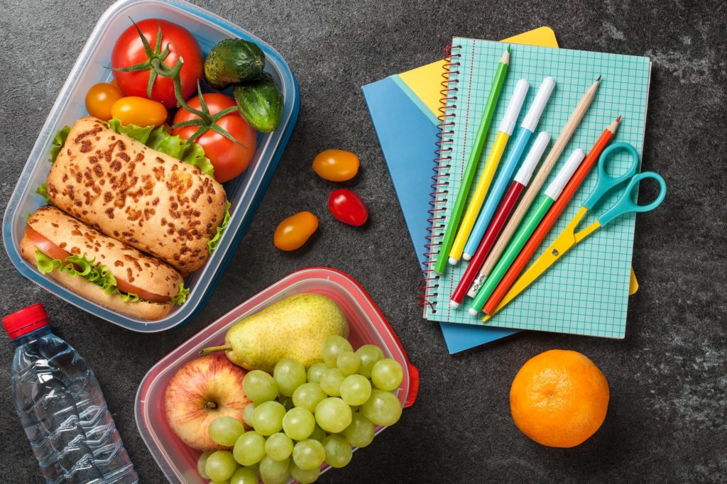 Lunch boxes and school supplies on black background